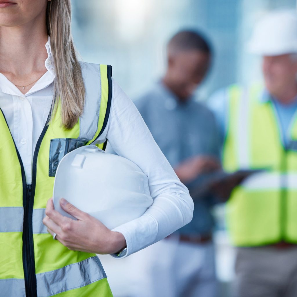 Kvinde står med sin sikkerhedshjelm på arbejdspladsen